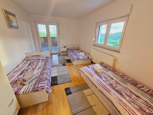 3 camas en una habitación con ventanas y suelo de madera en Čarobni pogled Zagreb, en Zagreb
