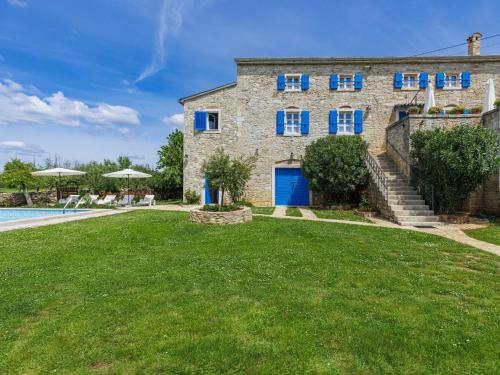 ein Steinhaus mit blauen Fenstern und einem Pool in der Unterkunft Holiday Home Graziela - PRC604 by Interhome in Sveti Lovreč Pazenatički