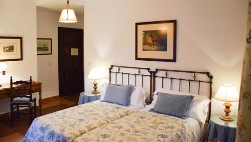 een slaapkamer met een bed, een bureau en 2 lampen bij Hotel Los Caspios in Colunga