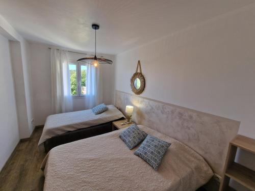 1 dormitorio con 2 camas y espejo en la pared en Appartement Piovanacce - T3 avec pisicne privée 10min de Saint-Florent en Barbaggio