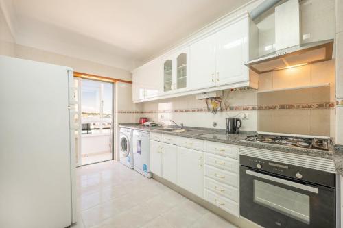 - une cuisine avec des placards blancs et un lave-linge/sèche-linge dans l'établissement GuestReady - Caparica Beach Lover's Dream, à Charneca