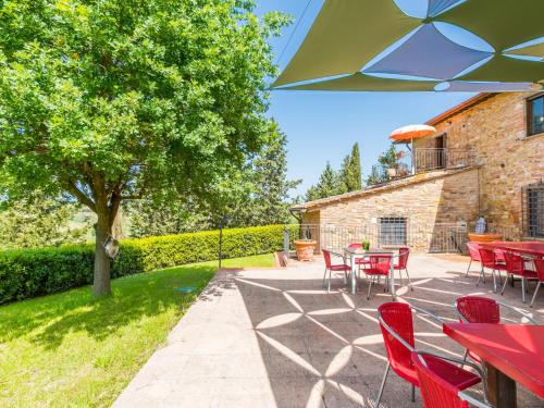 a patio with red tables and chairs and a tree at Apartment Casa Renai a San Gimignano-5 by Interhome in San Gimignano