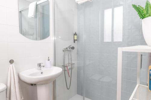 a white bathroom with a sink and a shower at Casa Luz del Carmen - Terraza, Primera Línea in Barbate