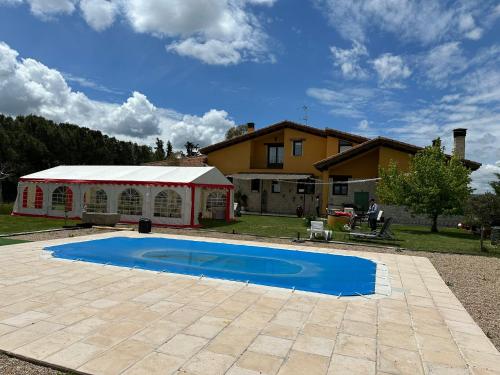 a swimming pool in front of a house with a tent at Un mar de pinares in Mata de Cuéllar