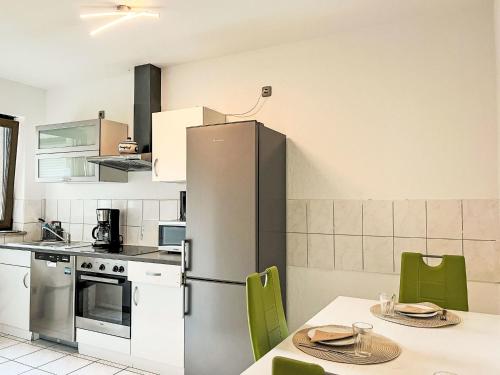 cocina con nevera de acero inoxidable y sillas verdes en Apartment Ferienapartments Adenau-1 by Interhome, en Adenau