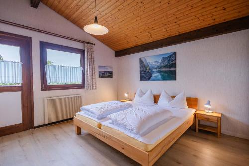 una camera da letto con un letto con lenzuola bianche e due lampade di Ferienwohnpark Immenstaad am Bodensee Satteldachhaus Typ 9 SD 19 a Immenstaad am Bodensee