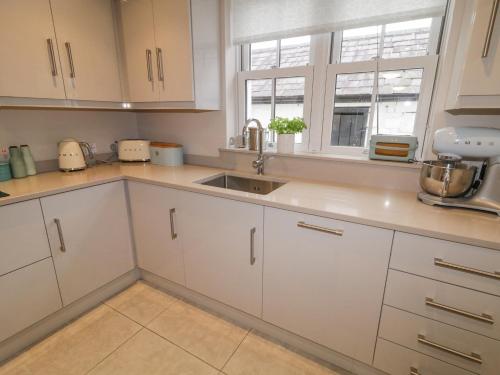 a kitchen with white cabinets and a sink at 3 Coastguard Station in Rathmullan