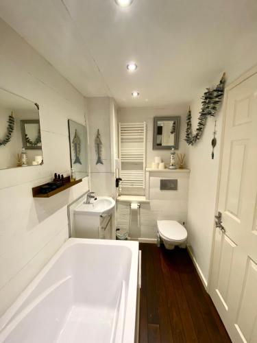 La salle de bains blanche est pourvue d'une baignoire et de toilettes. dans l'établissement Appartement cosy, spacieux & moderne - 95m2, à Lanslebourg-Mont-Cenis
