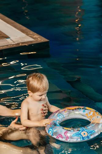 a young boy in a swimming pool next to a life preserver at Rest&Ski Spa Resort in Bukovel