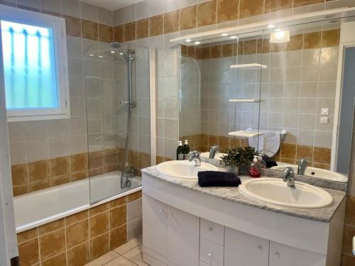 une salle de bain avec deux lavabos et un grand miroir dans l'établissement Oleander- Spacious Villa with Private Pool & Garden Sleeps 6, à Puimisson