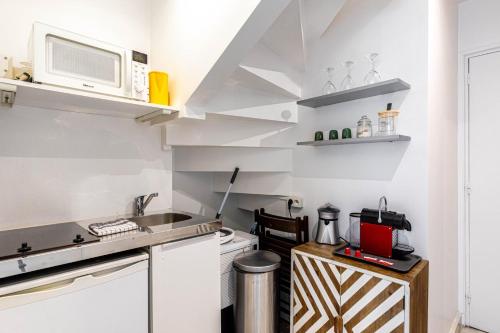 une cuisine avec des armoires blanches et un micro-ondes dans l'établissement GuestReady - Bel Apt. au cœur de Paris, à Paris