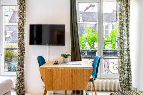 une pièce avec une table, des chaises et une télévision dans l'établissement GuestReady - Bel Apt. au cœur de Paris, à Paris
