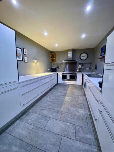 Il comprend une grande cuisine avec des placards blancs et du carrelage. dans l'établissement Appartement cosy, spacieux & moderne - 95m2, à Lanslebourg-Mont-Cenis