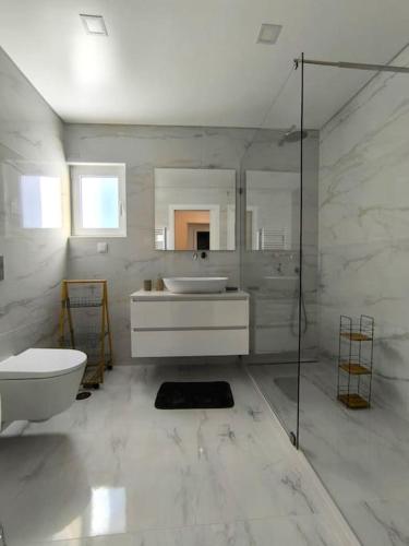 a white bathroom with a sink and a toilet at Full Nathur I Central Ericeira in Ericeira