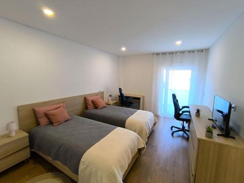 a bedroom with two beds and a television in it at Full Nathur I Central Ericeira in Ericeira