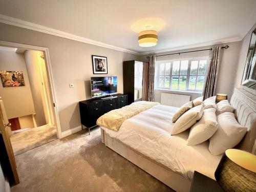 a bedroom with a large white bed with a window at Honey Hill Cottage - 4 Bedroom Detached House in Cambridge