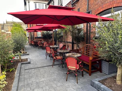 a patio with tables and chairs under a red umbrella at Chester House Guest House in Chester