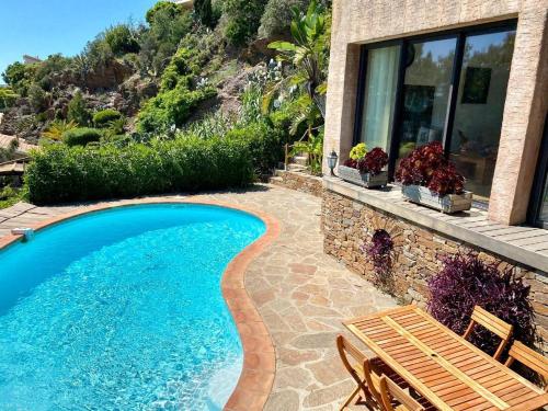 a swimming pool with a bench and a house at Villa les Alizés in Rayol-Canadel-sur-Mer