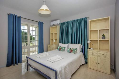 een slaapkamer met een groot bed en blauwe gordijnen bij Vila Ventura Marina in Albufeira