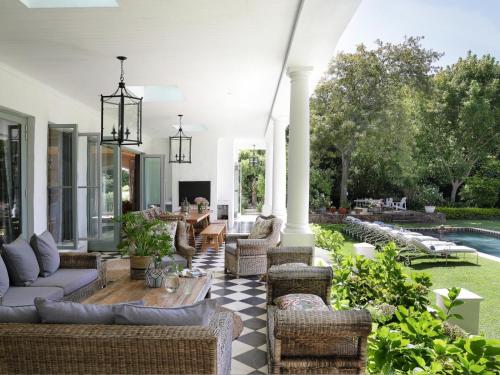 un patio al aire libre con muebles de mimbre y una piscina en Constantia Klein en Ciudad del Cabo