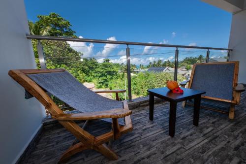 a rocking chair and a table on a balcony at Bijoutier Apartments in Grand'Anse Praslin