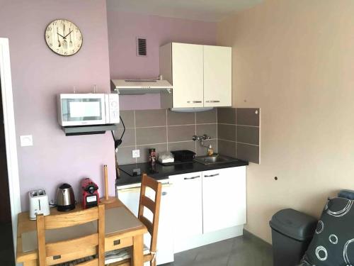 une petite cuisine avec des placards blancs et une horloge murale dans l'établissement Studio BAOBAB, à Chambéry