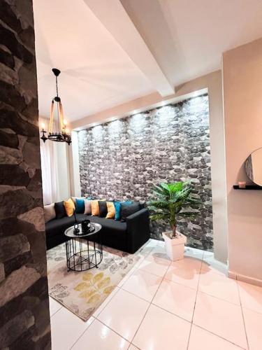 a living room with a black couch and a stone wall at [Front de mer] Appartement moderne avec terrasse in Al Houara