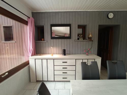 a room with a desk and two chairs and a clock at La véranda au domaine de Tara in LʼHôpital-du-Grosbois