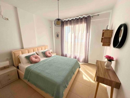 a bedroom with a bed with pink pillows on it at Tropicana Apartments in Dhërmi