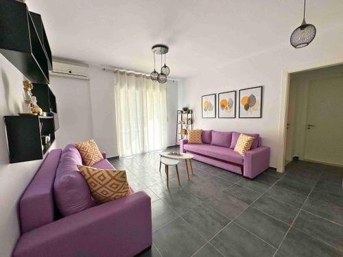 a living room with purple couches and a table at Tropicana Apartments in Dhërmi