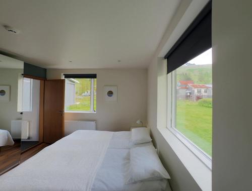 a bedroom with a large white bed with a large window at Seydisfjördur Guesthouse in Seyðisfjörður