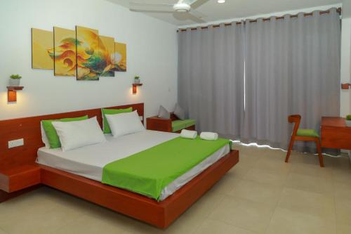 ein Schlafzimmer mit einem großen Bett und einem Stuhl in der Unterkunft Traveller's Hotel Hikkaduwa in Hikkaduwa