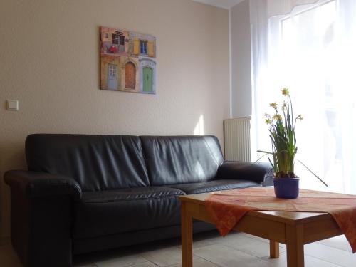 a black leather couch in a living room with a table at Futterküche in Haselünne