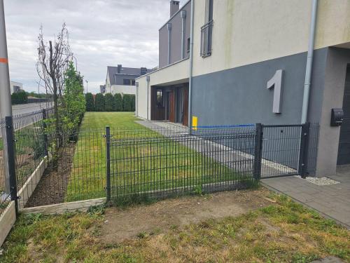 a fence in front of a building with a yard at Przytulne mieszkanie z kominkiem in Opole
