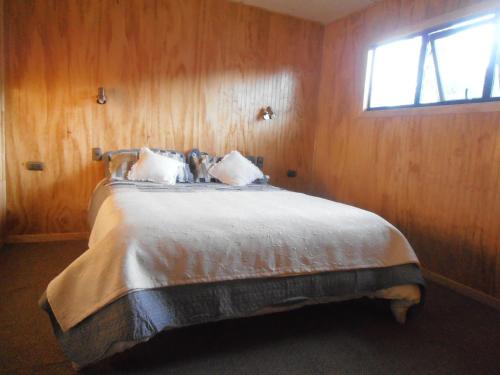 a bedroom with a bed in a wooden wall at Agroturismo Coñico in Quilquico