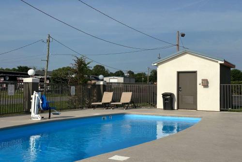 a swimming pool with two chairs next to a fence at Super 8 by Wyndham Monroe in Monroe