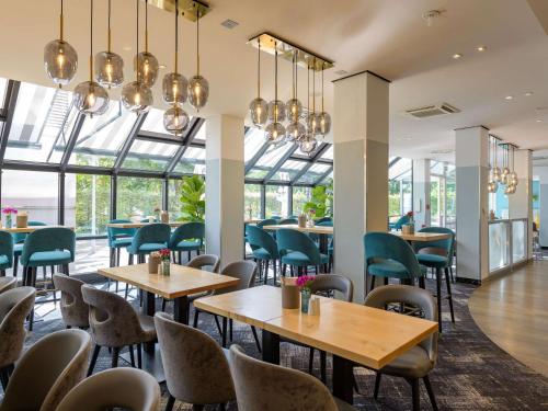 um restaurante com mesas, cadeiras e janelas em Mercure Hotel Köln West em Colônia