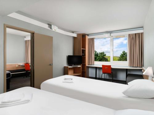 a hotel room with two beds and a desk at Ibis Budapest Citysouth in Budapest