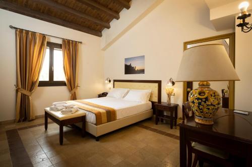 una camera con letto, tavolo e lampada di Badiula a Carlentini