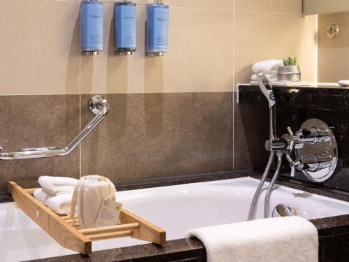 ein Badezimmer mit einer Badewanne und einem Tablett mit Handtüchern in der Unterkunft Sofitel London Heathrow in Hillingdon
