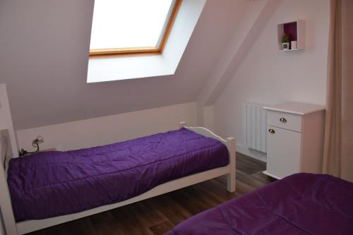 une chambre avec un lit violet et une fenêtre dans l'établissement Hébergement Plage du Débarquement - 6/10 pers, à Sainte-Mère-Église
