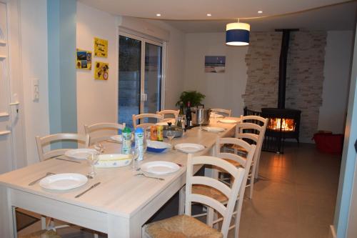 - une table à manger blanche avec des assiettes et des chaises blanches dans l'établissement Hébergement Plage du Débarquement - 6/10 pers, à Sainte-Mère-Église