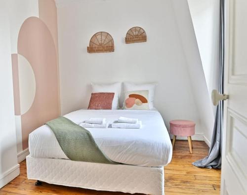une chambre avec un lit blanc avec des serviettes dessus dans l'établissement Appartement proche Montparnasse - Rose, à Paris