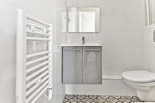 une salle de bain blanche avec des toilettes et un lavabo dans l'établissement Appartement proche Montparnasse - Rose, à Paris