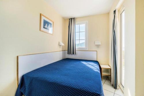 - un lit bleu dans une chambre avec fenêtre dans l'établissement Résidence le Hameau de Cap Esterel - maeva Home - Appartement 2 pièces 5 personnes - Confort MAE-9884, à Saint-Raphaël