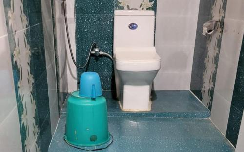 a bathroom with a toilet with a blue container on the floor at Dimmaliz Homestay by StayApart in Pedong
