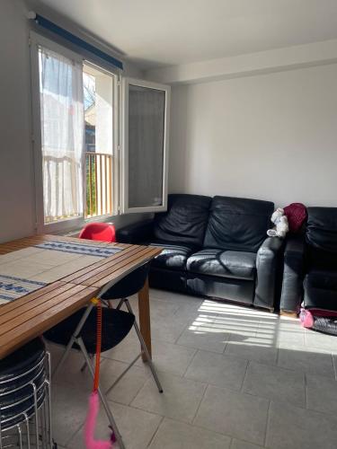 un salon avec un canapé noir et une table dans l'établissement Appartement - Villa Muguet, à Gagny
