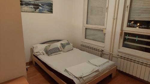 un piccolo letto in una camera con due finestre di Spacious Condo In Luxury Complex Belville, Belgrade a Novi Beograd
