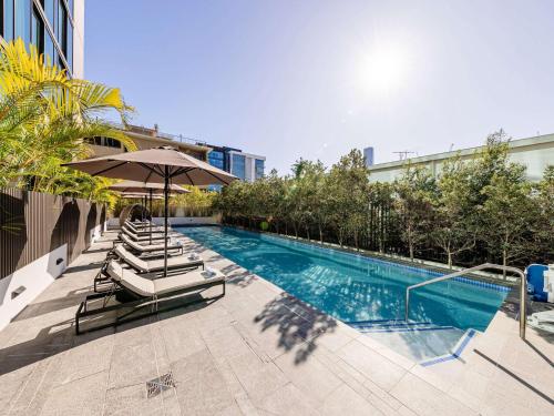 uma piscina com espreguiçadeiras e um guarda-sol em Novotel Brisbane South Bank em Brisbane