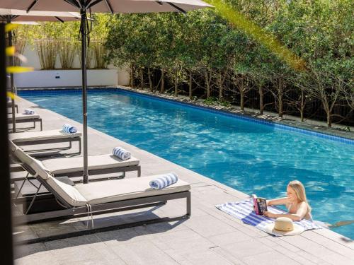 a woman laying on a towel in a swimming pool at Novotel Brisbane South Bank in Brisbane
